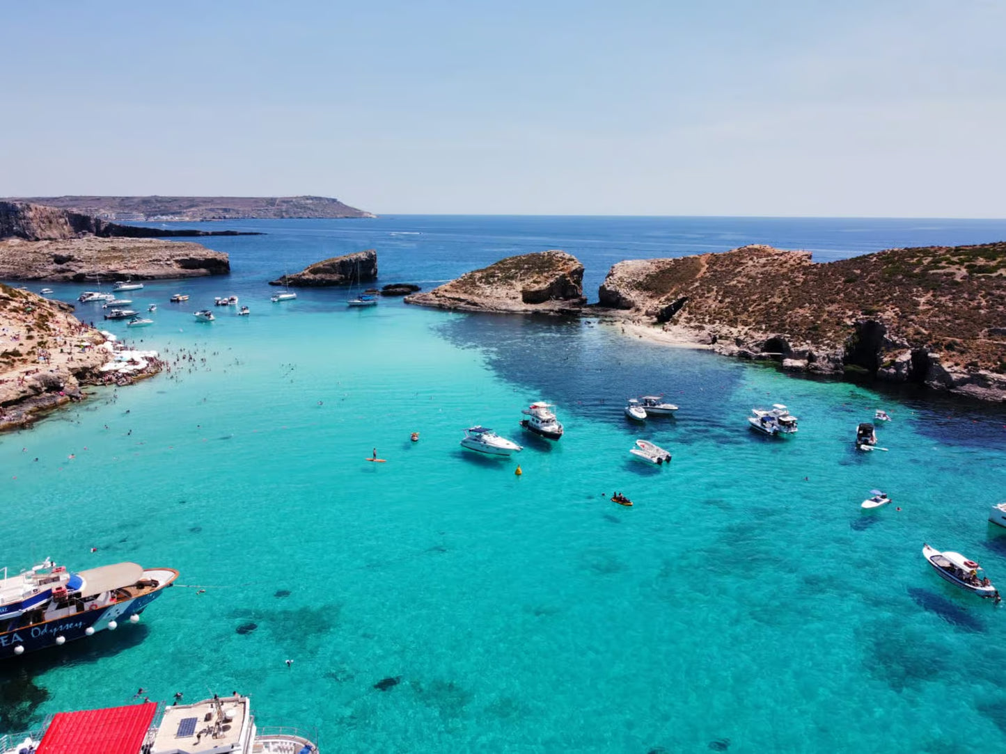 Turquoise waters with boats and rocky cliffs under a clear blue sky