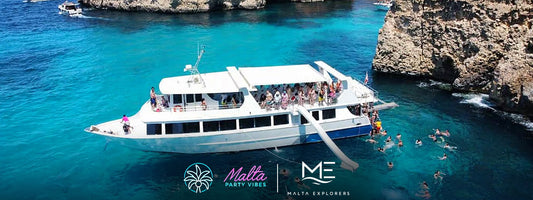 Bateau de croisière Malta Explorers ancré dans l'eau turquoise au large de Comino, nageurs près du toboggan