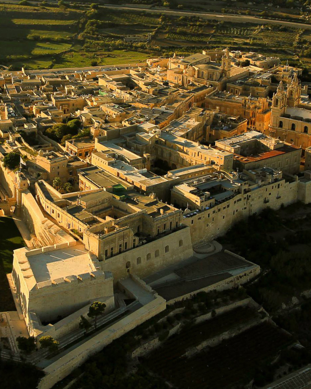 Aerial view of a historic stone city with narrow streets and buildings.