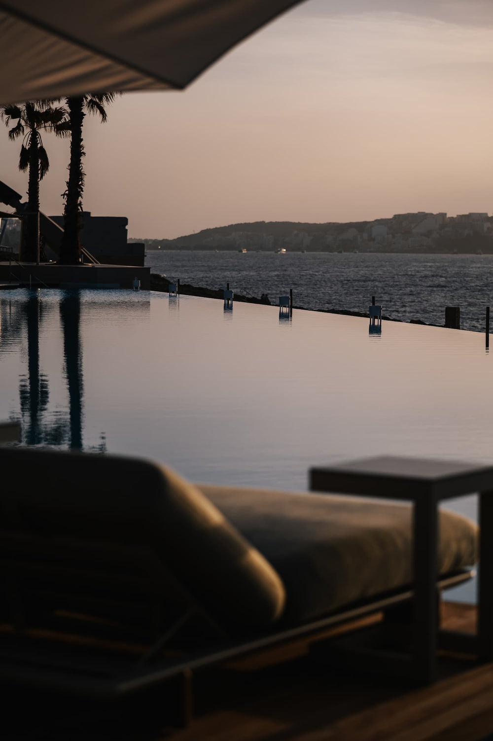 The infinity pool of Café del Mar Malta at dusk, on the edge of the Mediterranean