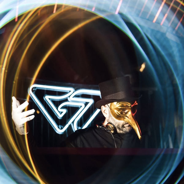 Claptone con la sua maschera dorata durante un DJ set a Malta, tra scie di luce