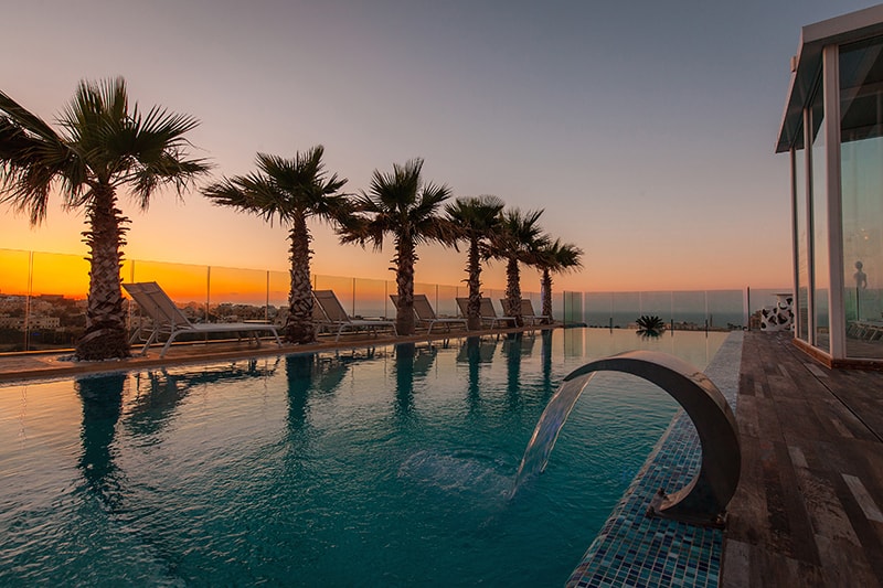 La piscina infinita y las palmeras de Infinity by Hugo's al atardecer