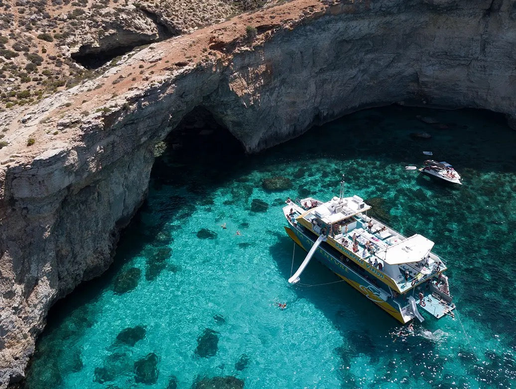 Boat party in Malta in a turquoise bay near sea cliffs