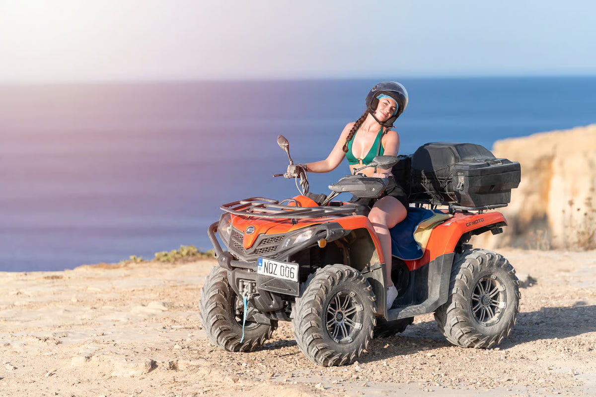 Femeie cu cască pe un ATV, lângă ocean