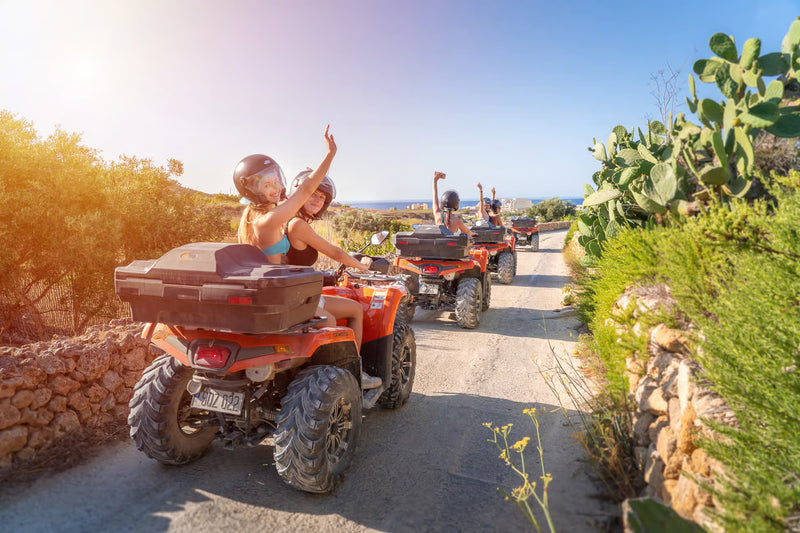 People riding ATVs on a scenic trail with cacti and greenery.
