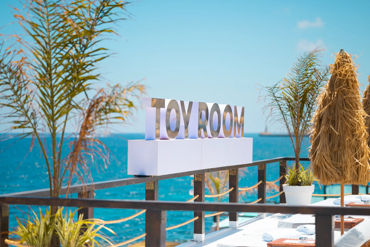 Het bord van Toy Room Beach Club boven de zee aan de Qui-Si-Sana-boulevard, Sliema